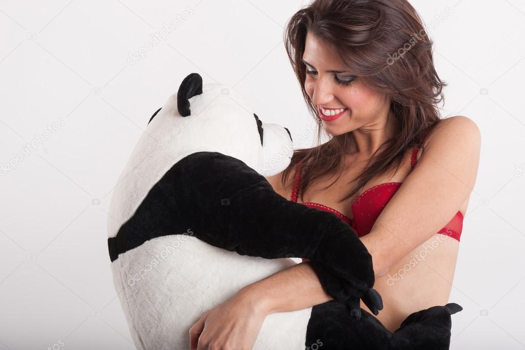 Smiling and sexy woman embracing teddy bear panda