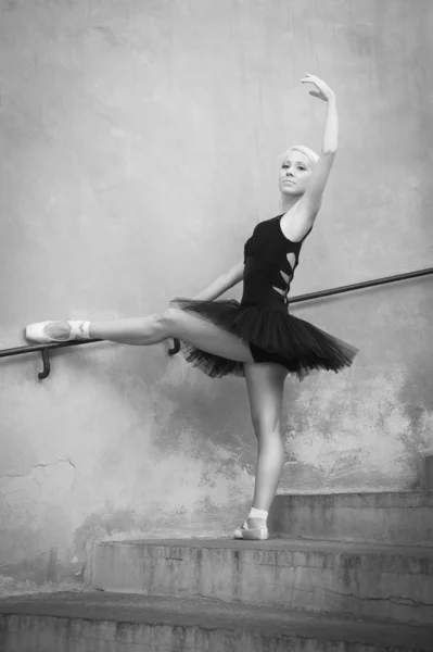 年轻美丽的芭蕾舞演员摆坐在楼梯上。黑色和 wh — 图库照片