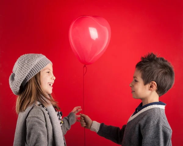 Un par de niños con globos rojos en el fondo rojo. Valent. — Foto de Stock