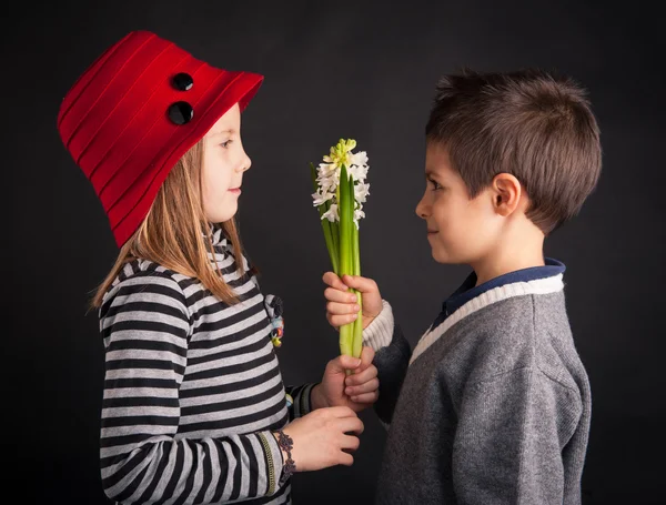 Junge bietet Blume auf schwarzem Hintergrund. Valentinstag-Konzept. — Stockfoto