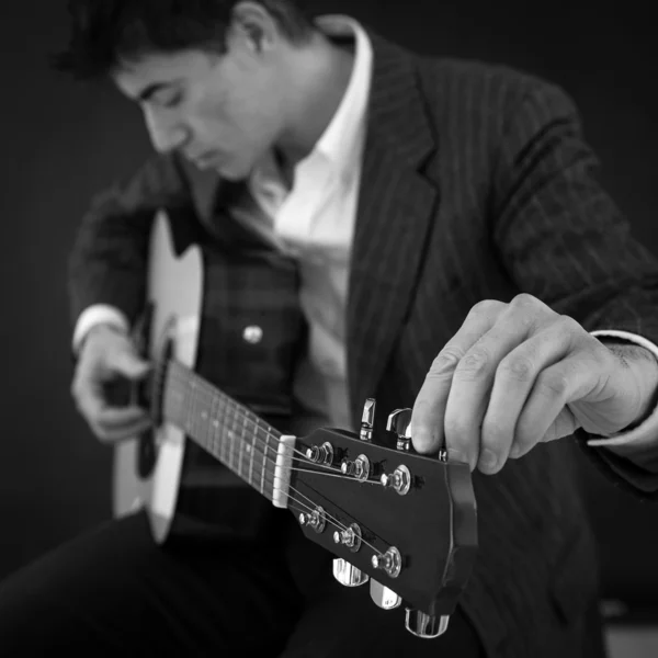 Homem de acordo com guitarra contra fundo preto. Preto e branco i — Fotografia de Stock