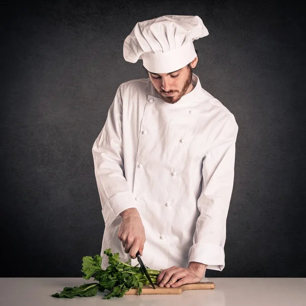 Retrato de un joven cocinero con una sartén con uniforme sobre fondo grunge — Foto de Stock