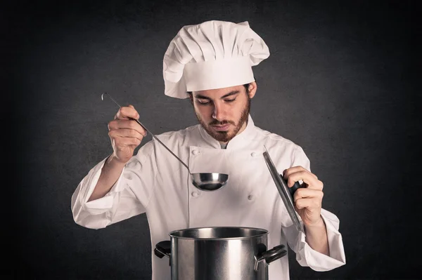 Portrait of a young cook man with pan wearing uniform over grunge background — Stock Photo, Image