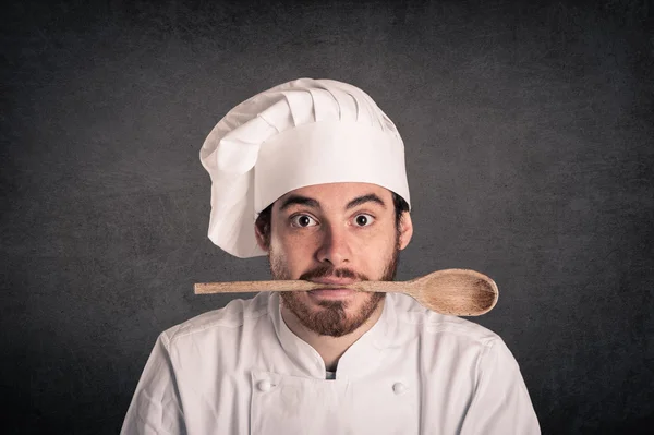 Portrait of a young cook man with pan wearing uniform over grunge background — Stock Photo, Image