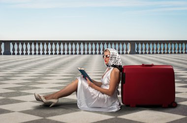 Retro kadın güneş gözlüğü ve bavul kitap portre açık havada deniz önünde okuma.