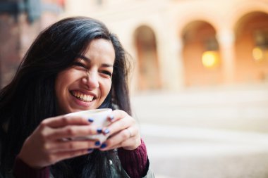 Smiling woman drinking coffee in a cafe outdoors. Shallow depth of field. clipart