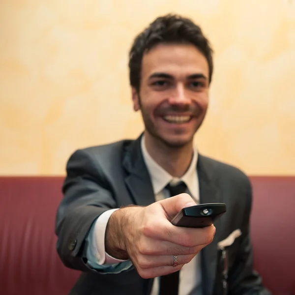 Happy business man pointing remote control. Selective focus image. — Stock fotografie