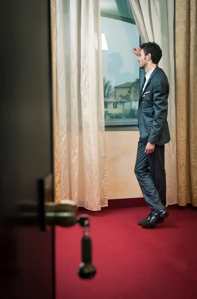 Einsamer Mann am Fenster im Hotelzimmer. — Stockfoto