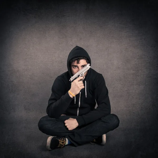 Young killer with gun portrait over dark grunge background. — Stock Photo, Image