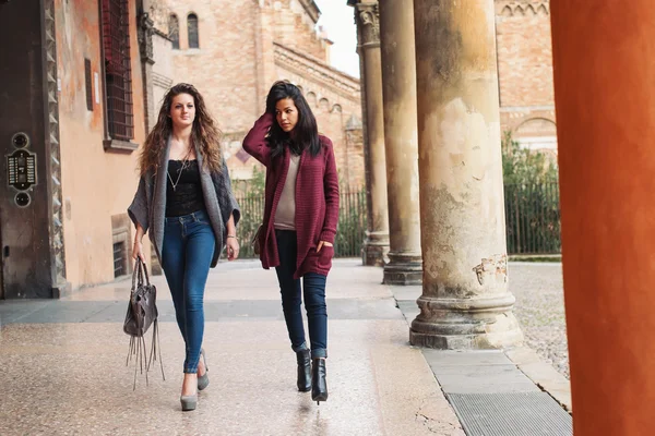 Twee meisjes lopen buiten saint stephen vierkante, bologna, Italië. volledige lichaam. — Stockfoto