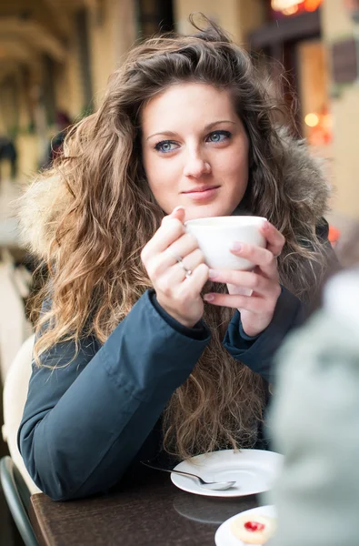 Młoda kobieta picia kawy w kawiarni na świeżym powietrzu. Płytkiej głębi ostrości. — Zdjęcie stockowe