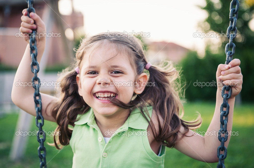 Little smiling girl swinging close up portrait.