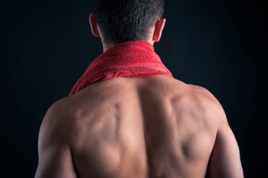 arkadan görünüşü genç adam gömleksiz siyah arka plan kırmızı havlu ile.