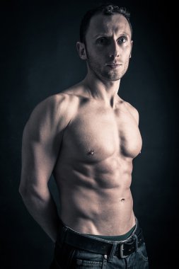 Kendine güvenen genç adam gömleksiz portre siyah arka plan.