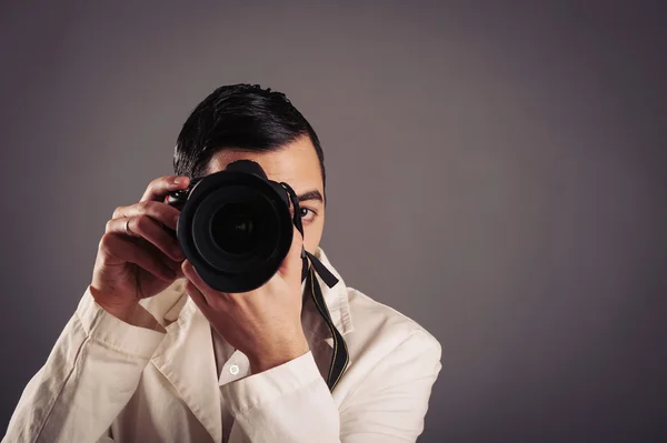 Hombre sosteniendo la cámara sobre fondo oscuro . — Foto de Stock