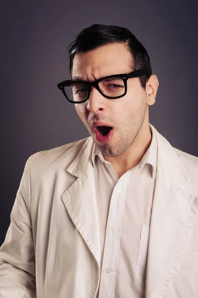 Retrato divertido de un joven nerd con anteojos sobre fondo gris . —  Fotos de Stock