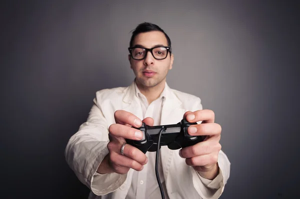 Jonge nerd met brillen holding joystick en spelen geïsoleerd op donkere achtergrond. — Stockfoto
