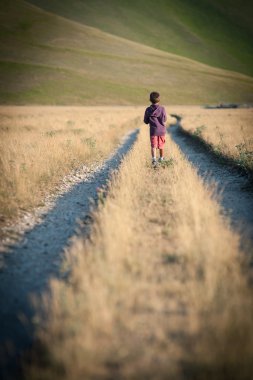 Yalnız açık havada yürüyen bir çocuk. castelluccio di norcia, monti sibillini park, İtalya.