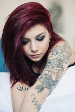 şehvetli yatakta yatarken dövmeli güzel kız portresi.