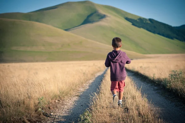 Yalnız açık havada yürüyen bir çocuk. castelluccio di norcia, monti sibillini park, İtalya.