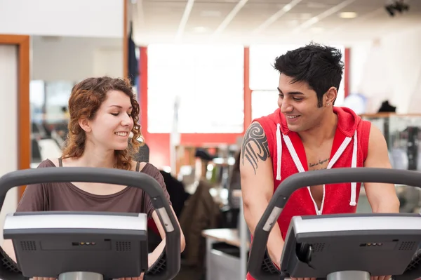 Jeune couple de formation dans la salle de gym avec vélo tout en parlant ensemble . — Photo