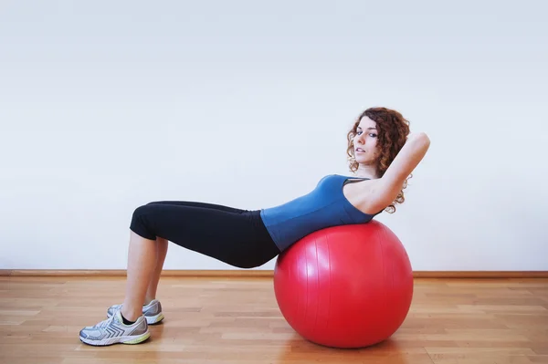 Молодая женщина упражнения с мячом в тренажерном зале . — стоковое фото