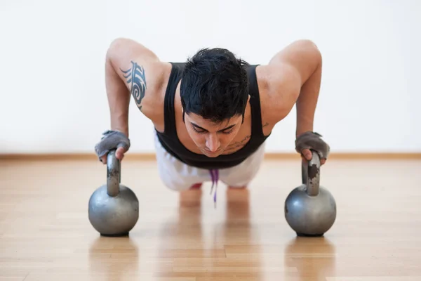 Young man training in the gym with heavy balls. — Stock Photo, Image