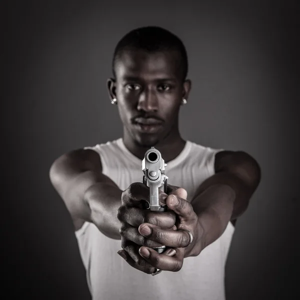Killer with gun close up over dark background. Focus on gun. — Stock Photo, Image