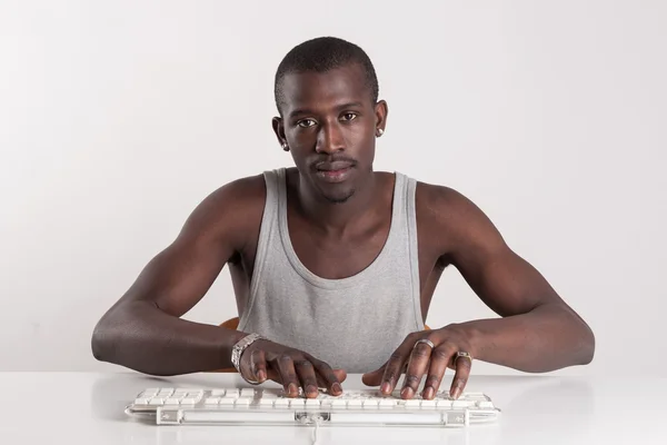 Jonge Afrikaanse man met toetsenbord kijken camera geïsoleerd op witte achtergrond. — Stockfoto