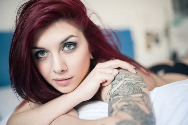 şehvetli yatakta yatarken dövmeli güzel kız portresi.