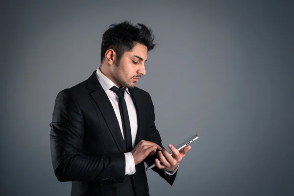Jonge zakenman kijken naar Tablet PC op donkere achtergrond. — Stockfoto