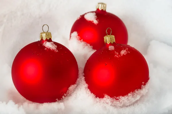 Trois boules de Noël rouges sur la neige — Photo