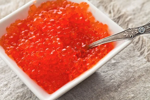 Caviar rojo en un tazón y cuchara —  Fotos de Stock