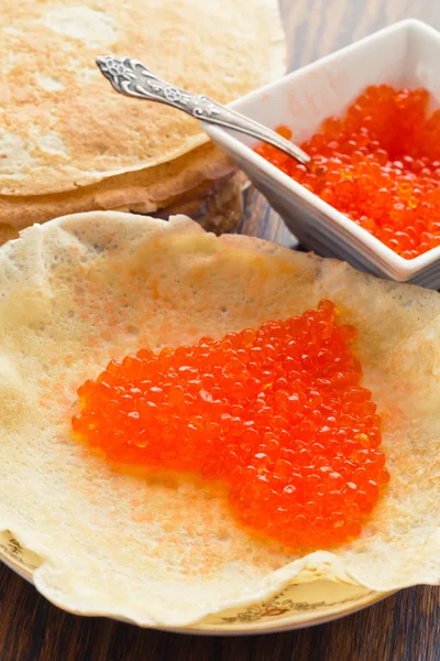 Pfannkuchen mit rotem Kaviar in Herzform lizenzfreie Stockbilder