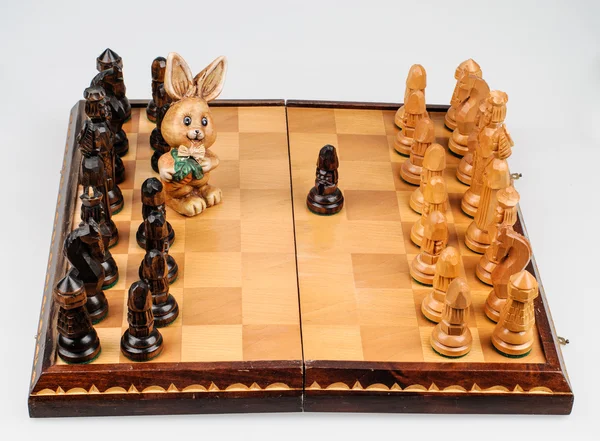 Vyřezávaného zajíce mezi šachové figurky — Stock fotografie