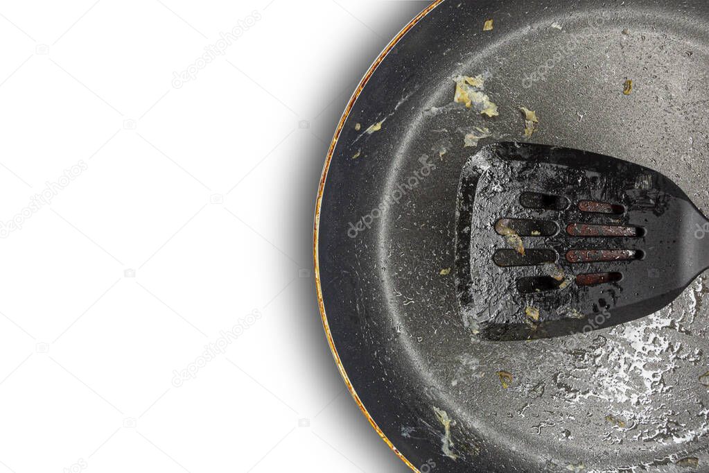 Fragment of a dirty frying pan and frying pan spatula on a white background. Copy space. Concept.