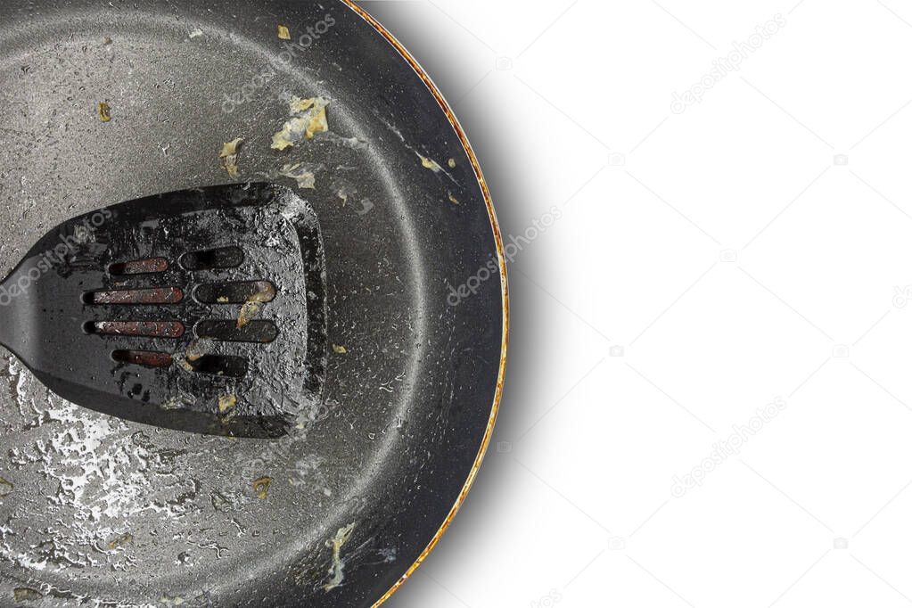 Fragment of a dirty frying pan and frying pan spatula on a white background. Copy space. Concept.