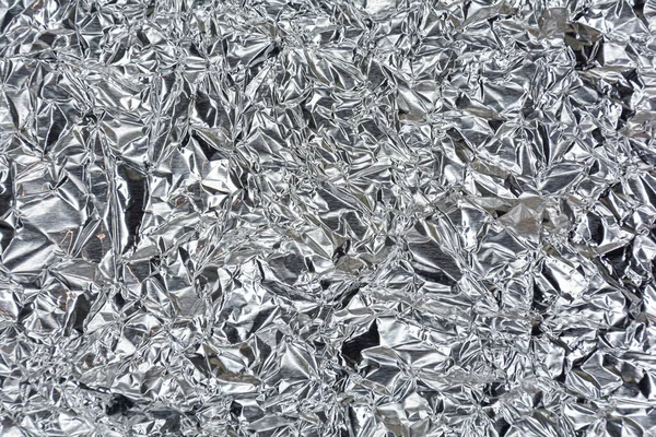 Arka planda parlak bir nane yüzeyi olan gümüş folyo. Gümüş renk ve doku arkaplanı