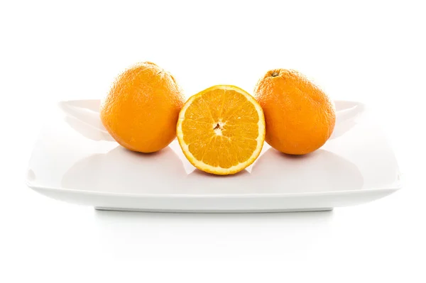 Naranjas sobre plato blanco sobre fondo blanco —  Fotos de Stock