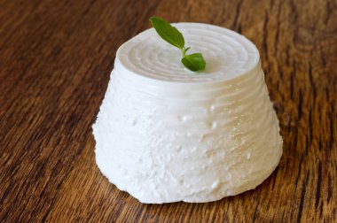 fresh ricotta with basil leaf on wooden table clipart