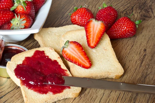 Jordbærsyltetøy med rusk på trebord – stockfoto