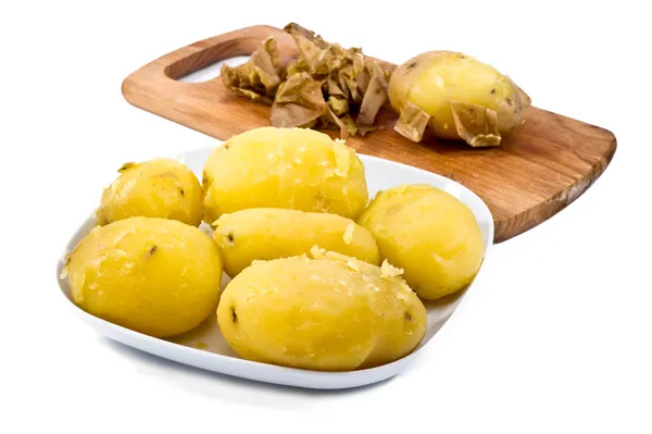 Peeled potatoes with wooden board in background — Stock Photo, Image