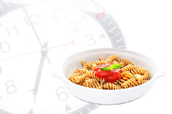 Pâtes au basilic et sauce tomate avec horloge sur fond — Photo