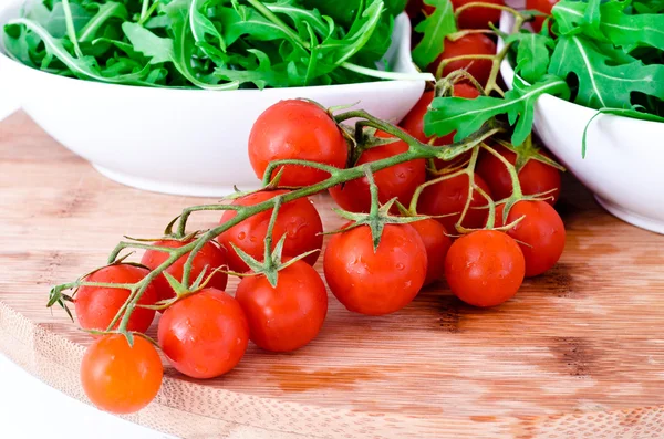 Tomatoes and rucola in white cups over wooden board — Stock Photo, Image