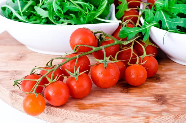 Pomodori e rucola in tazze bianche su tavola di legno — Foto Stock