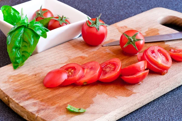 Deska do krojenia z pomidorami i bazylia, liść — Zdjęcie stockowe