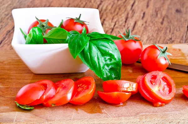 Deska do krojenia z pomidorami i bazylia, liść — Zdjęcie stockowe