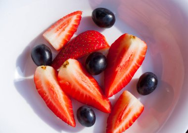 Beyaz bir tabakta çilek ve üzüm