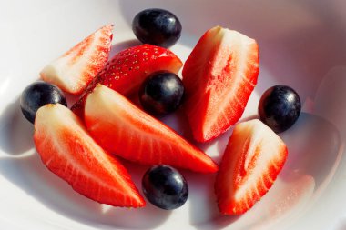 Beyaz bir tabakta çilek ve üzüm