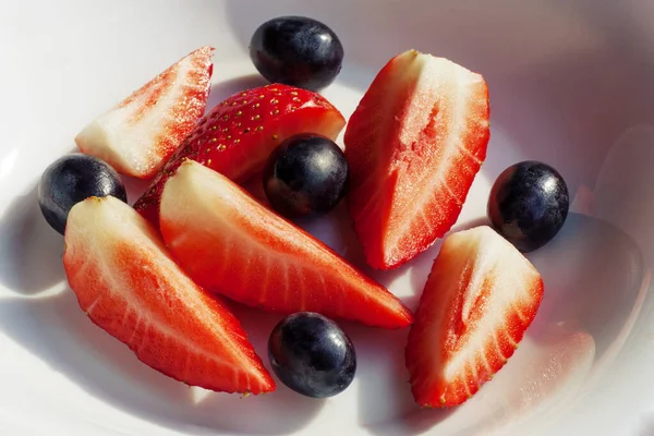 Beyaz bir tabakta çilek ve üzüm